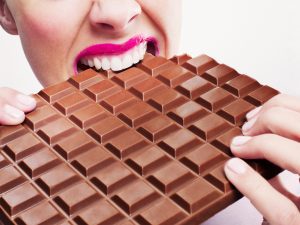 Woman in pink lipstick biting large chocolate bar
