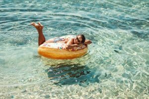 A beautiful young woman swims on inflatable ring donut at the sea water and enjoys on vacation.